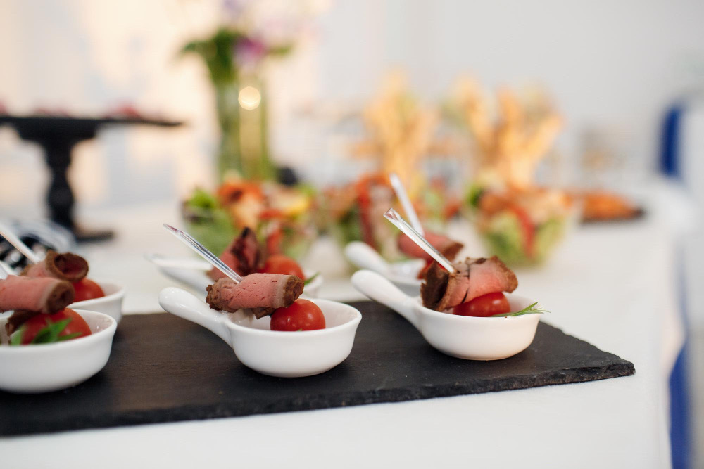 Aperitivos de carne y tomate servidos en cucharas sobre pizarra